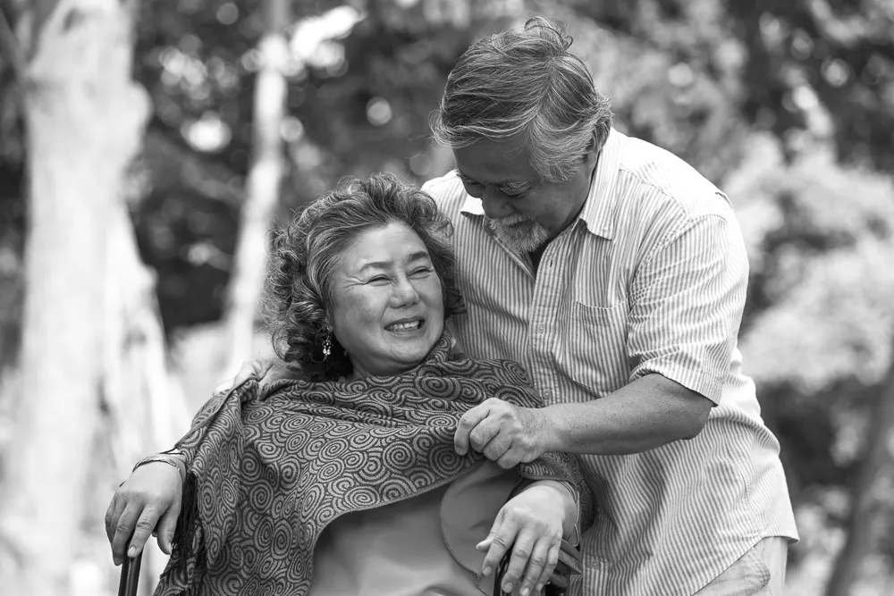 Una pareja disfrutan del tiempo juntos al aire libre mientras él le cubre los hombros con un chal