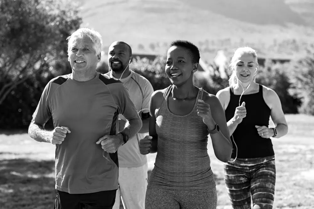 Un grupo de personas corriendo al aire libre  mientras se ayudan a estar activos para mantener la salud de su cerebro