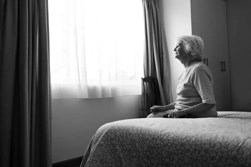 Una mujer sentada al borde de su cama después de despertar de una noche de sueño reparador