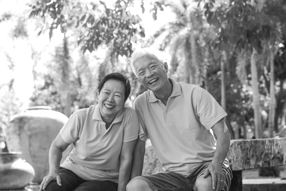An older couple sitting outside, enjoying fresh air and laughing with friends