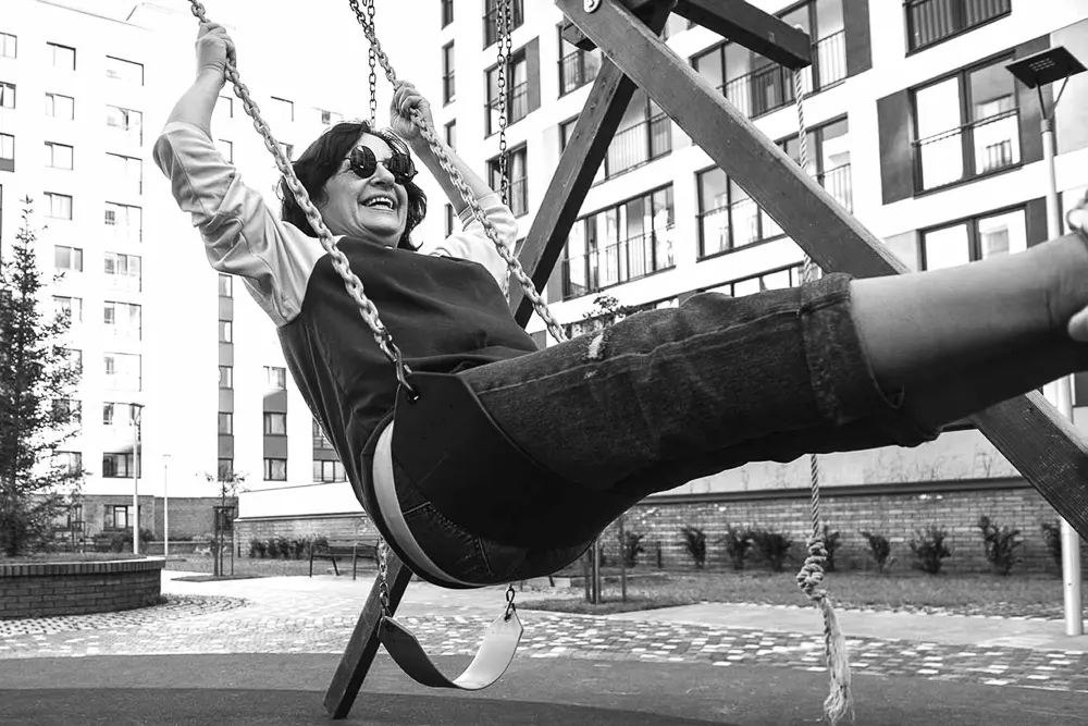 A woman taking a break from her daily routine to swing on a swingset and enjoy the sunshine
