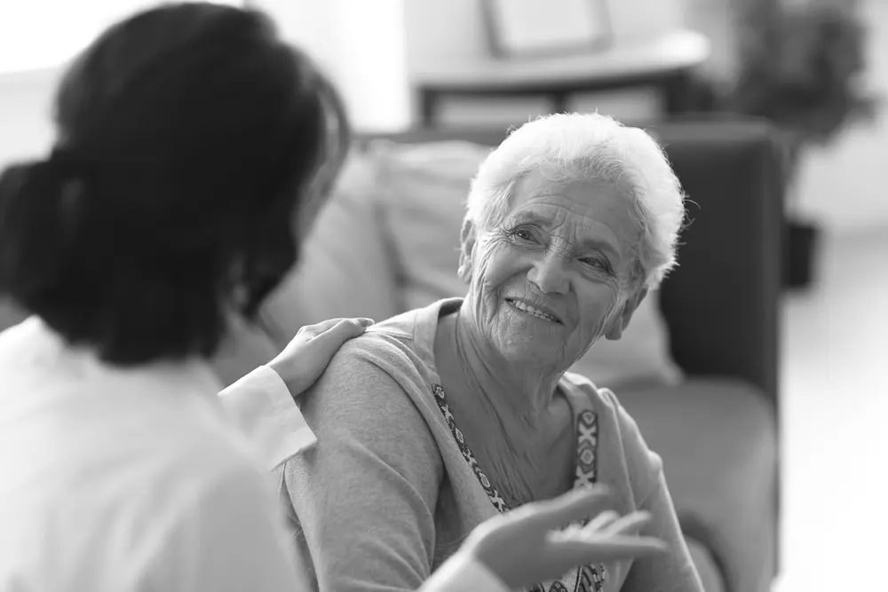 Mujer mayor sentada en un sofá con su médico mientras discuten las diferentes etapas de la enfermedad de Alzheimer